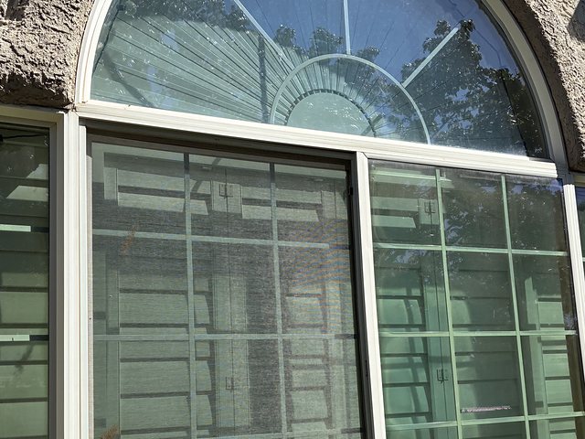 Arched window with dirty glass and screen before cleaning